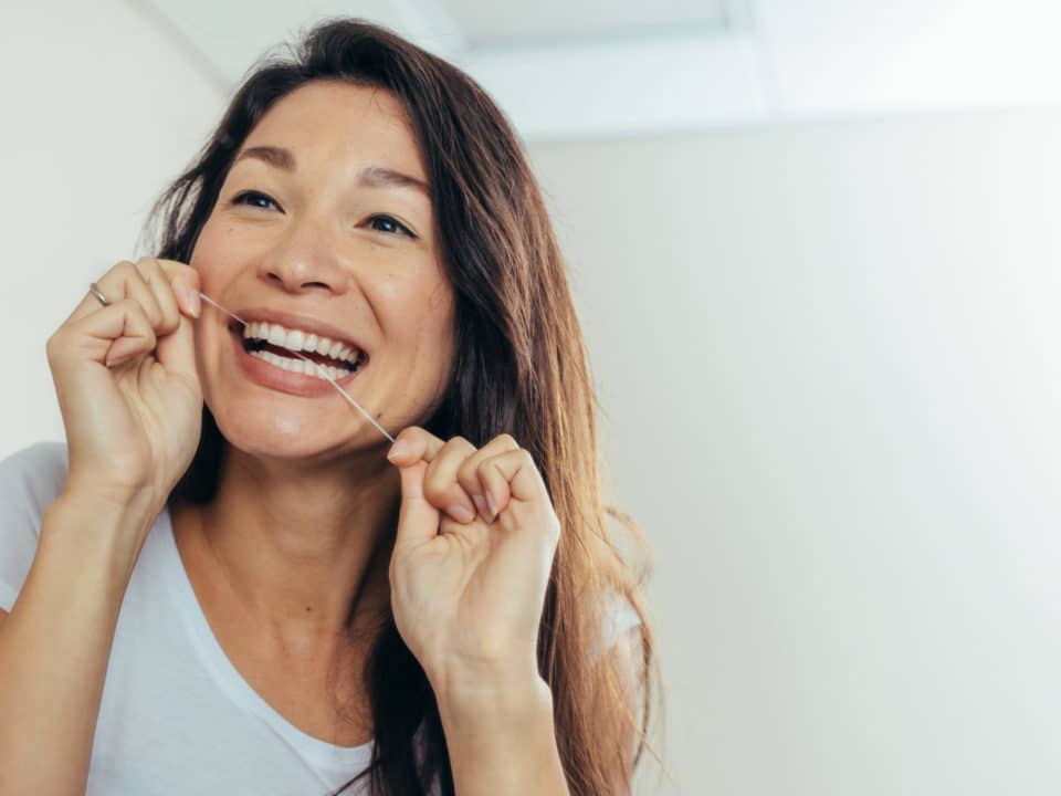 Woman flossing at dental implant dentist in Washington MI